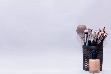 Makyaj fırçaları gri bir arka planda duruyor. Makyaj sanatçıları sadece profesyonel fırça kullanır..