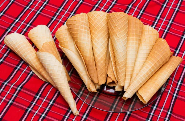 Boş gofret ruloları, kırmızı masa örtüsünde boynuzlar. Sevgi olarak favori tüp.