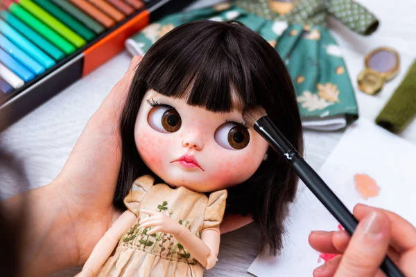 The puppet master creates a new face for the puppet. Blythe dolls are made to order.