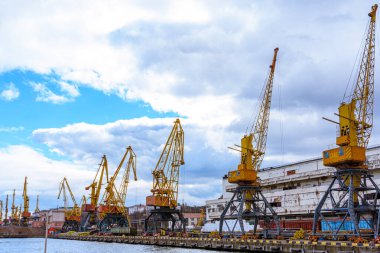 Odessa, UKRAINE - 1 Mart 2021. Sarı iskele vinçleri ticari bir gemiyi yüklemeye hazır. İskele vinçleri Karadeniz 'de bir rıhtımda duruyor..