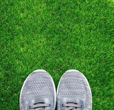 Yeşil çimlerde gri spor ayakkabılar. 