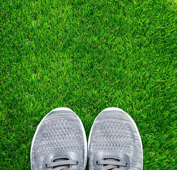 Yeşil çimlerde gri spor ayakkabılar. 