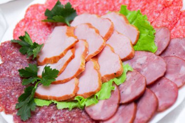 Bir tabakta dilimlenmiş sosis ve pastırma.