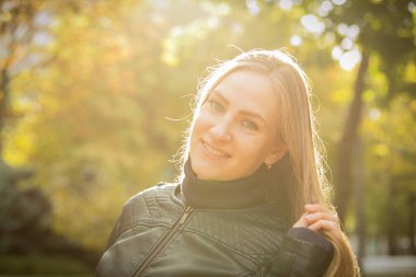 Sonbahar ağaçlarının arka planında güzel genç bir kadın. Duygu konsepti. Sonbahar parkında yürü. Arka plan çekimi.