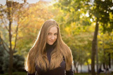 Sonbahar ağaçlarının arka planında güzel genç bir kadın. Duygu konsepti. Sonbahar parkında yürü.