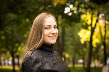 Sonbahar ağaçlarının arka planında güzel genç bir kadın. Duygu konsepti. Sonbahar parkında yürü.