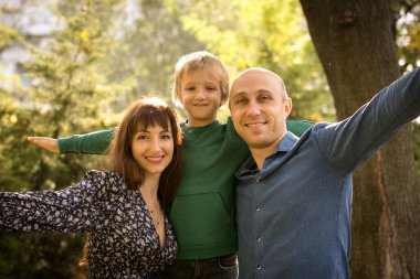 Düş! Mutlu aile - anne, baba ve oğul sonbahar parkında yürüyüş yaparken. Duygu konsepti. Oğlanın ve ailesinin keyfi yerinde..