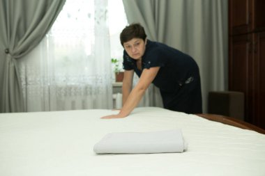 Ev ödevi. Orta yaşlı bir kadın yeni yatak örtüsü takıyor..