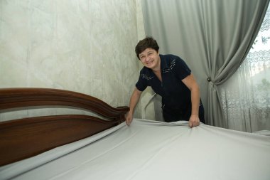 Ev ödevi. Orta yaşlı bir kadın yeni yatak örtüsü takıyor..