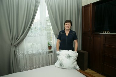 Ev ödevi. Orta yaşlı bir kadın yeni yatak örtüsü takıyor..