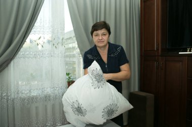 Ev ödevi. Orta yaşlı bir kadın yeni yatak örtüsü takıyor..