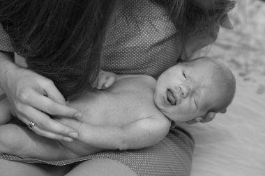 Annenin elleri bebeği dikkatlice tutuyor. Ciddi ve güzel bir bebek uyuyor. Annelik şefkati kavramı.