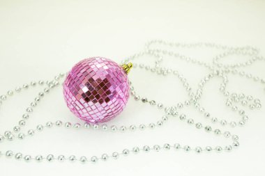 Yeni yıl ve Noel kartı. Beyaz kardaki ayna parçalarından pembe top. Yeni yıl oyuncağının etrafında gümüş boncuklar. Minimalizm kavramı.