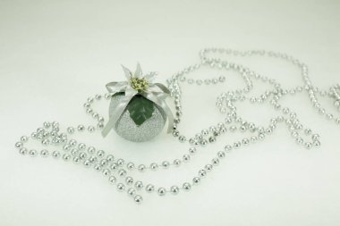Yeni yıl ve Noel kartı. Beyaz kar üzerinde Noel süsü olan gümüş top. Yeni yıl oyuncağının etrafında gümüş boncuklar. Minimalizm kavramı.
