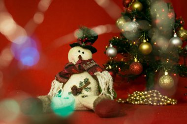 Kırmızı arka planda yeni yıl ve yılbaşı kartı. Neşeli kardan adam ve Noel ışıkları.