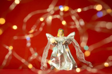 Kırmızı arka planda yeni yıl ve yılbaşı kartı. Noel beyaz meleği ve ışıklar.