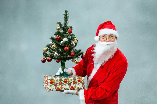 灰色背景下的圣诞老人画像 圣诞老人带着礼物和一棵漂亮的圣诞树 情感概念 — 图库照片