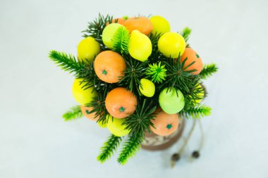 Çamur kabında parlak turuncu mandalina ve sarı limon buketi. Buket yeşil yapraklarla süslenmiş. El yapımı sabundan meyveler..