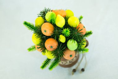 Çamur kabında parlak turuncu mandalina ve sarı limon buketi. Buket yeşil yapraklarla süslenmiş. El yapımı sabundan meyveler..