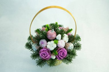 Hasır sepetteki parlak pembe ve beyaz çiçek ve koni buketi. Buket köknar dallarıyla süslenmiş. El yapımı sabun çiçekleri.