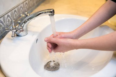 Ergen. Banyo lavabosunda ellerini yıkıyorsun. Sık sık el yıkama, koronavirüs salgınına karşı iyi hijyen için bir ön koşuldur..
