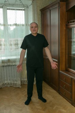 Sabah egzersizleri. Yaşlı bir adam evde jimnastik yapıyor. Karantina süresince tüm spor merkezleri kapalıdır..