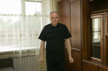 Sabah egzersizleri. Yaşlı bir adam evde jimnastik yapıyor. Karantina süresince tüm spor merkezleri kapalıdır..