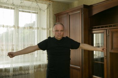 Sabah egzersizleri. Yaşlı bir adam evde jimnastik yapıyor. Karantina süresince tüm spor merkezleri kapalıdır..