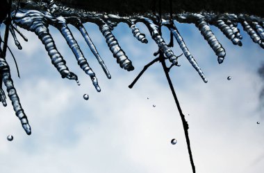 Buz saçakları. Kış. Buz saçakları gökyüzüne karşı eriyor.