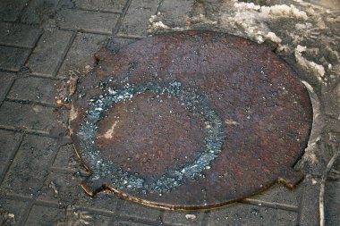 Yolda bir kapak var. Kanalizasyon tıkanmış. Su kapaktan çıkar ve hemen donar. Kışın sert dondurucu soğuklar.