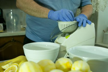 Evde limoncello limonata yapma süreci. Bir adam yemek makinesine limon suyu sıkıyor..