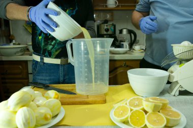 Evde limoncello limonata yapma süreci. Mutfakta iki adam çalışıyor. Biri limon suyunu yemek makinesine sıkıyor, diğeri limonları zevksiz bir şekilde kesiyor..
