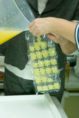 Evde limoncello limonata yapma süreci. İki kadın taze sıkılmış limon suyunu buz torbalarına döker..