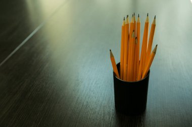 Ahşap bir masanın üzerinde siyah plastik bir kalem kılıfındaki kalemler. Öğrenme kavramı.