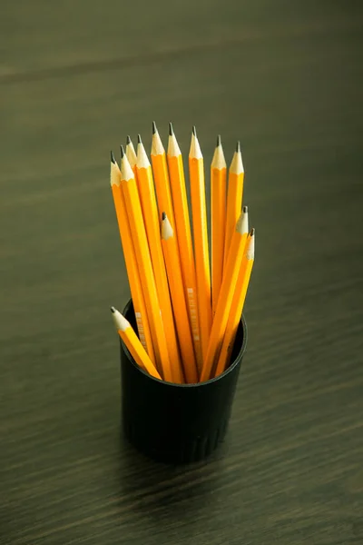 Pencils in a black plastic pencil case on a wooden table. Learning concept.