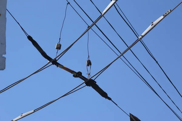 Overhead electric transmission lines against blue sky background. Industrial electric cable lines passing overhead against the clear sky background.