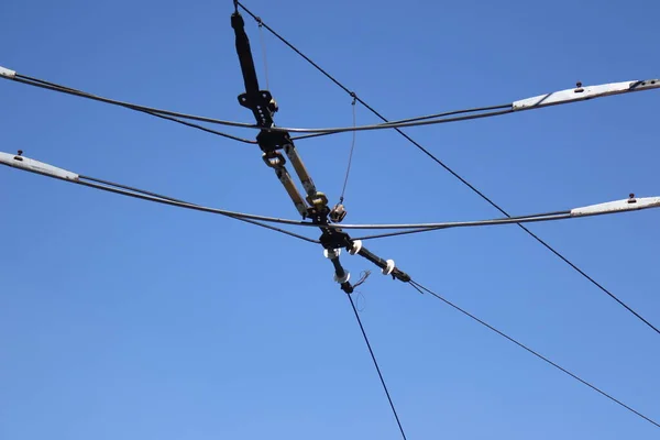 Overhead electric transmission lines against blue sky background. Industrial electric cable lines passing overhead against the clear sky background.