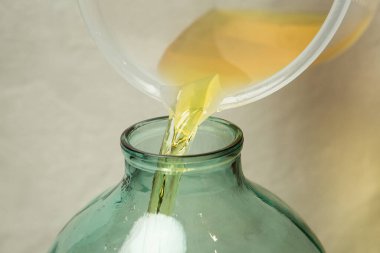 Evde limoncello limonata yapma süreci. Bir adam limon aromalı filtrelenmiş alkolü on litrelik cam şişeye doldurur..