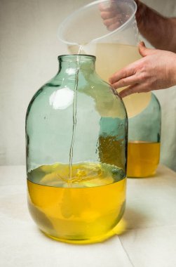 Evde limoncello limonata yapma süreci. Bir adam on litrelik bir şişede limonlu alkolle şeker şurubunu karıştırır..
