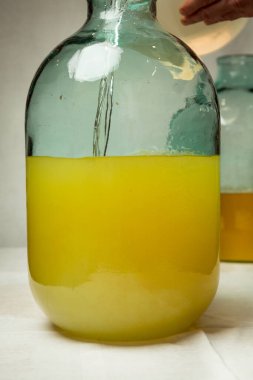 Evde limoncello limonata yapma süreci. Bir adam on litrelik bir şişede limonlu alkolle şeker şurubunu karıştırır..