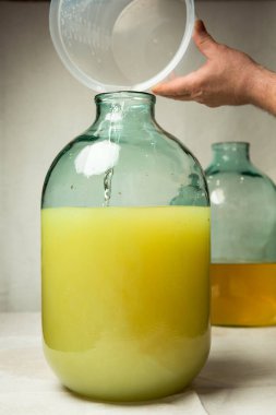 Evde limoncello limonata yapma süreci. Bir adam on litrelik bir şişede limonlu alkolle şeker şurubunu karıştırır..