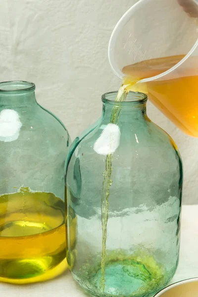 리몬첼로 리큐어를 집에서 만드는 남자가 주스와 알코올을 리터짜리 유리병에 붓는다 — 스톡 사진