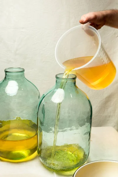 리몬첼로 리큐어를 집에서 만드는 남자가 주스와 알코올을 리터짜리 유리병에 붓는다 — 스톡 사진