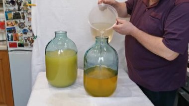 Evde limoncello limonata yapma süreci. Bir adam on litrelik bir şişede limonlu alkolle şeker şurubunu karıştırır..