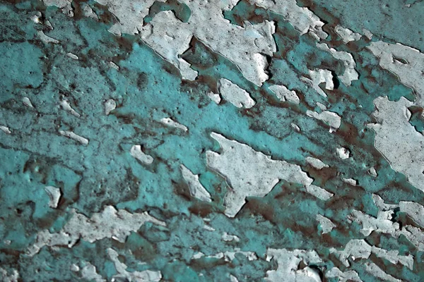 Peeling paint on the wall. Concrete wall with old cracked peeling paint. Weathered rough painted surface with patterns of cracks and peeling. Texture for background and design.