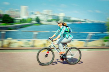 Hareket bulanıklığı. Genç bir kadın şehir seti boyunca bisiklet sürüyor..