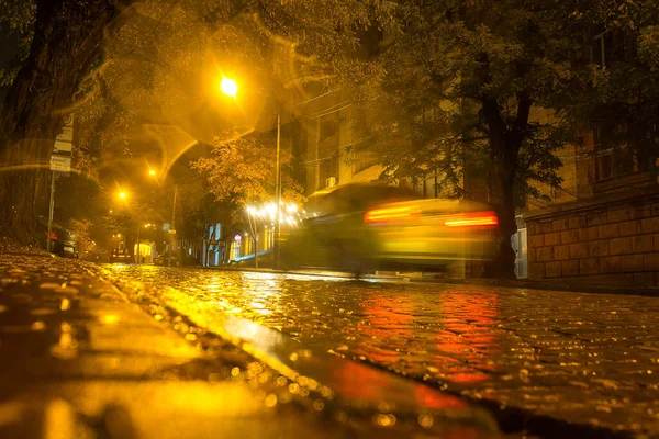 The speed of the car on the road in the city. Evening city in autumn during the rain. Motion blur.