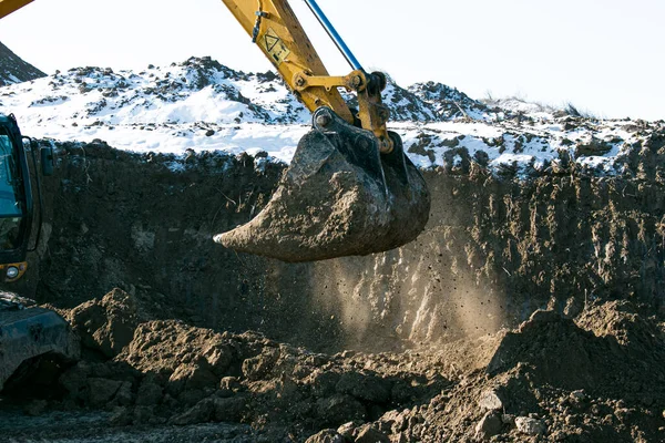 Crawler excavator. Earth-moving machine at a construction site. The excavator in the process of work digs up the earth and pours it onto the site. Works on a clear winter day.