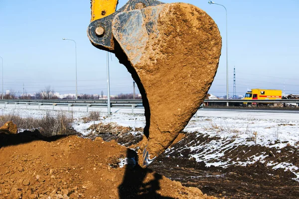 Crawler excavator. The excavator in the process of work digs out the earth and pours it onto the site. Works on a clear winter day against the blue sky.