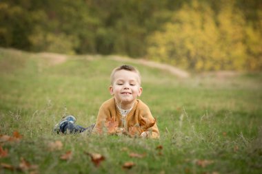 Düş! Sonbahar ormanının arka planında küçük bir çocuğun yakın çekimi..
